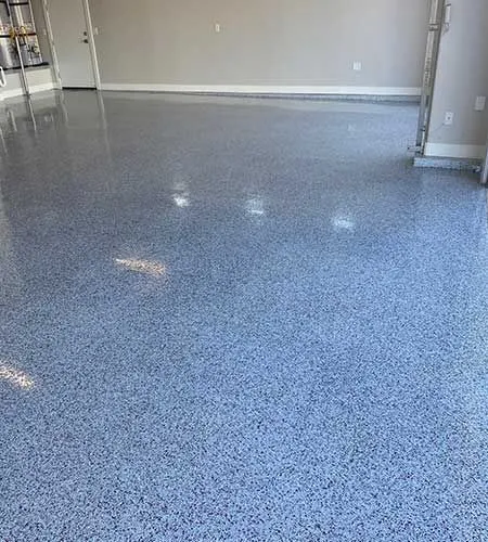 Epoxy-coated garage floor with blue and gray chips, reflecting light.