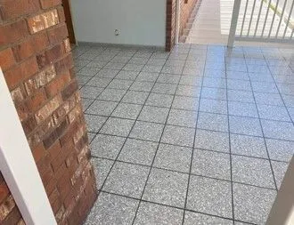 Gray tiled floor with brick wall and doorway.
