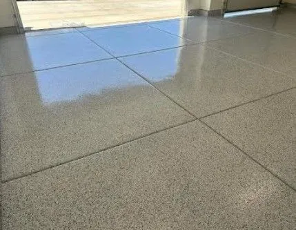 Polished concrete floor in a garage; gray, glossy surface with grid lines, reflecting sky.