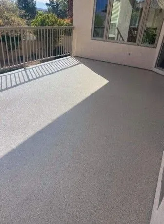 Gray textured concrete patio with sunlight and a railing.