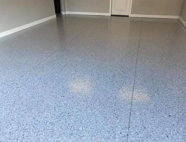 Gray epoxy garage floor with speckled finish, reflecting light.