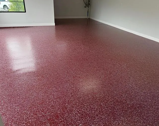 Red speckled epoxy floor in a room with white walls and a window.